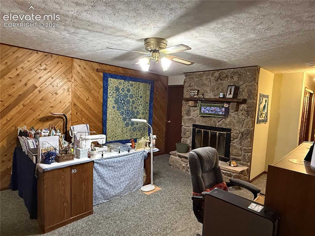 Image 16 of 38: Living area featuring a stone-faced fireplace with a wood mantle, wood plan