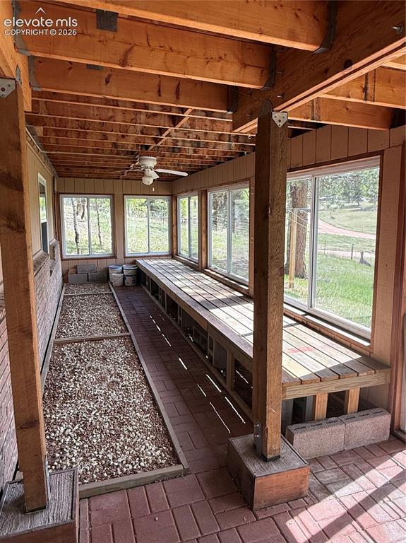 Image 18 of 38: Sunroom featuring exposed wood beams, multiple large windows, brick paver f