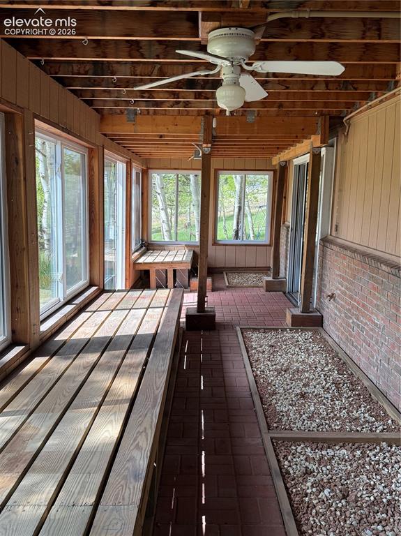 Image 19 of 38: Enclosed porch featuring wood plank flooring, brick paver accents, exposed