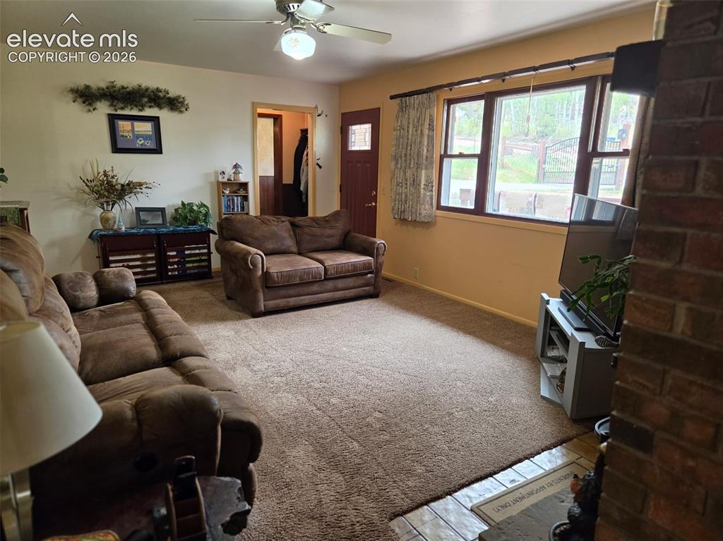 Image 2 of 39: Spacious living area featuring carpeted flooring and an exposed brick accen
