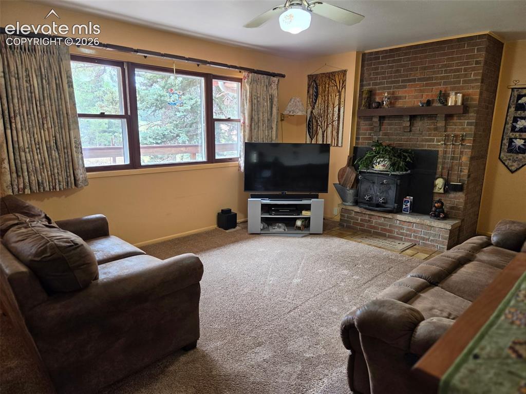 Image 3 of 39: Living area featuring a brick fireplace with a wood-burning stove, a wood m