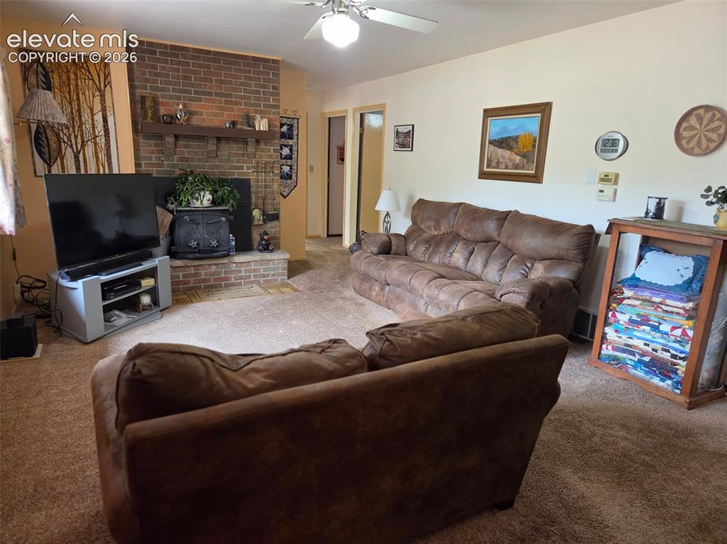 Image 4 of 39: Living area featuring a brick fireplace with a wood mantle, a ceiling fan,