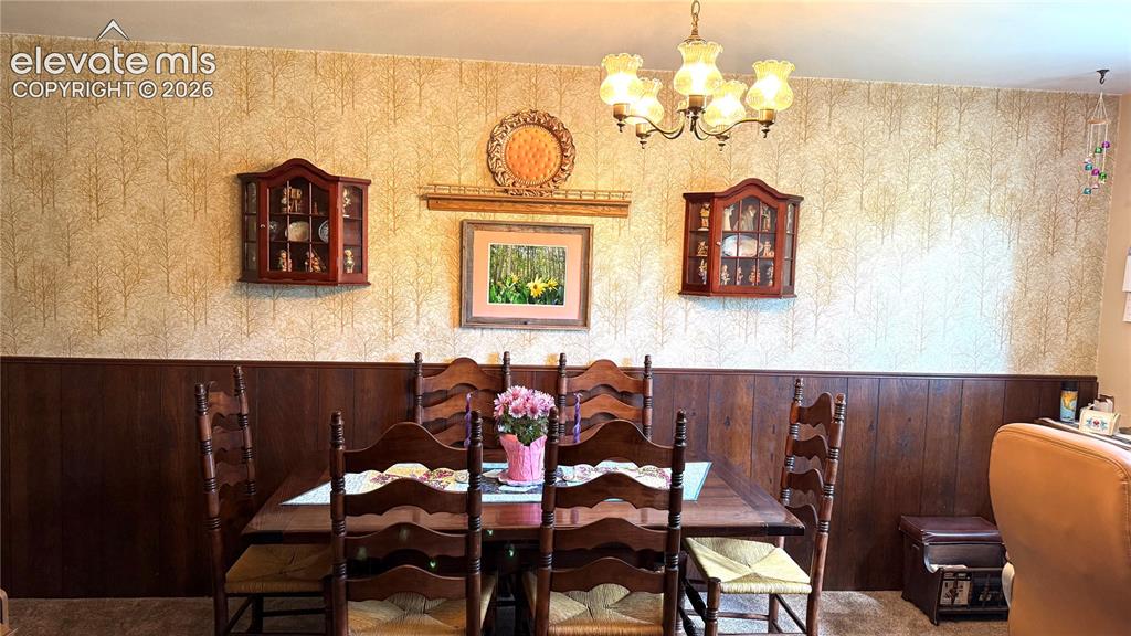 Image 5 of 38: Dining area featuring a wood-panel accent wall and patterned wallpaper