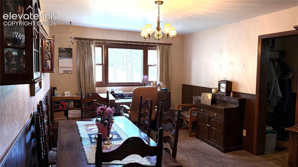 Image 6 of 38: Dining area featuring wood-finish paneling, a multi-pane window, and a chan