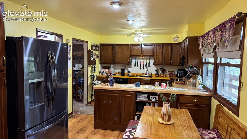 Image 7 of 38: Kitchen featuring wood-finish flooring, dark wood cabinetry, and light coun