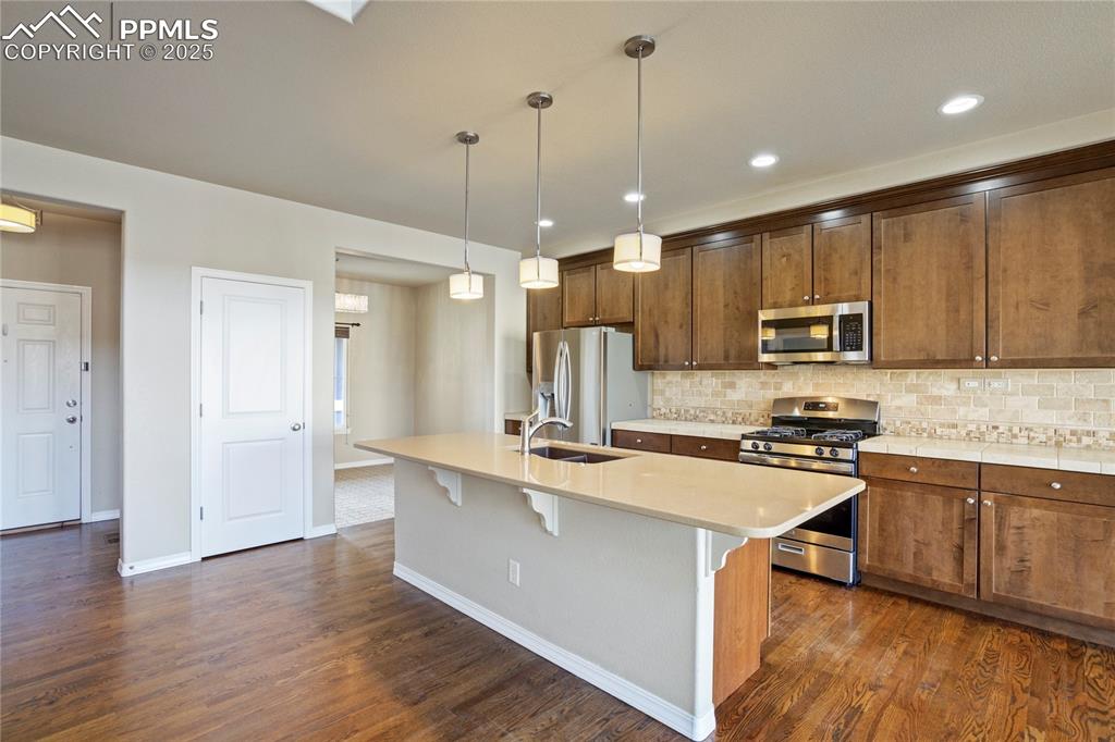 Image 11 of 50: Kitchen featuring stainless steel appliances, decorative backsplash, a cent