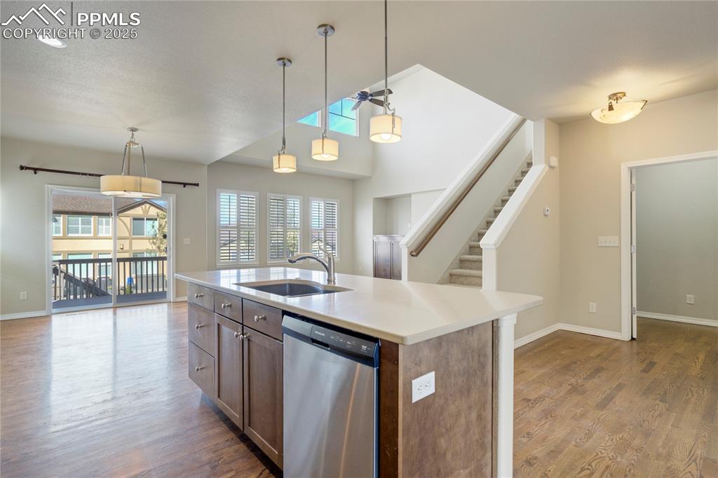 Image 12 of 50: Kitchen featuring hanging light fixtures, stainless steel dishwasher, dark 