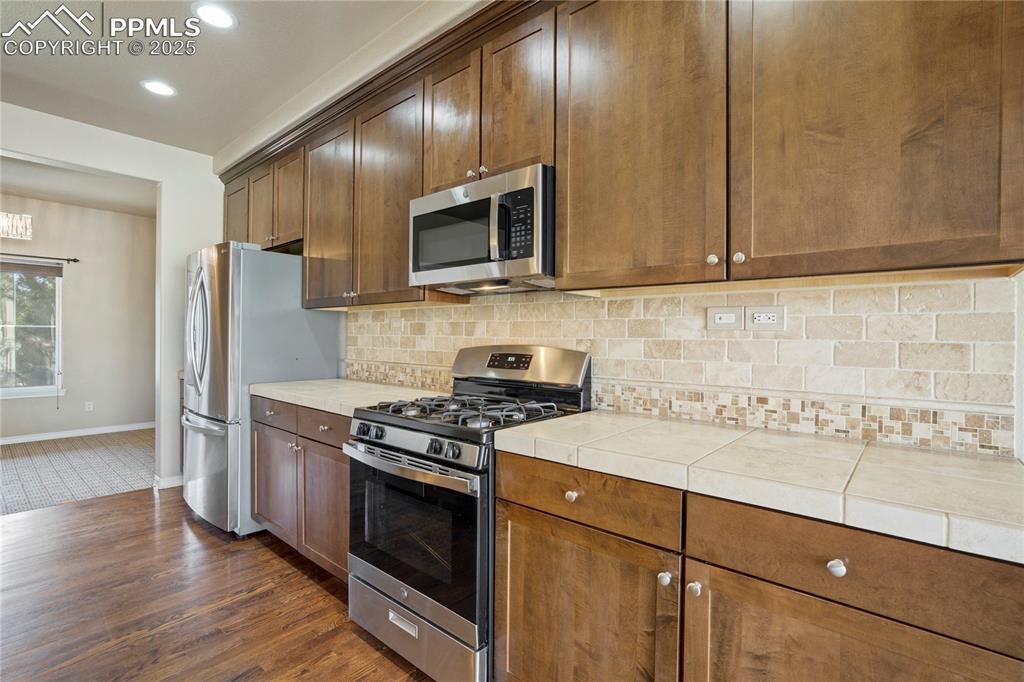 Image 13 of 50: Kitchen featuring appliances with stainless steel finishes, decorative back