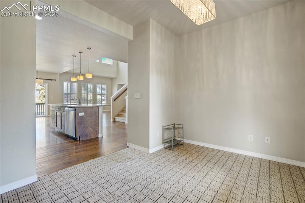 Image 14 of 50: Unfurnished room with stairway, a chandelier, and dark wood-style flooring