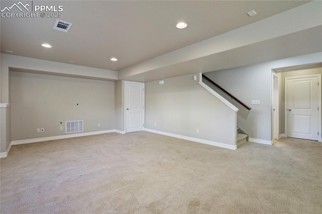 Image 33 of 50: Spare room featuring light colored carpet, recessed lighting, and stairway