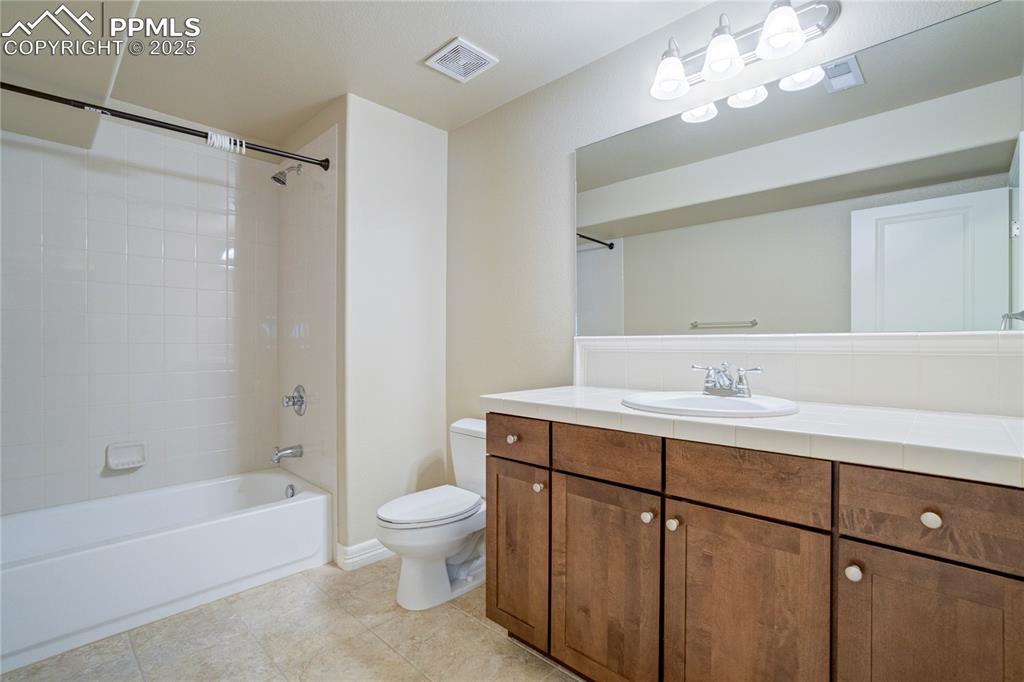 Image 37 of 50: Bathroom with tub / shower combination, vanity, and light tile patterned fl