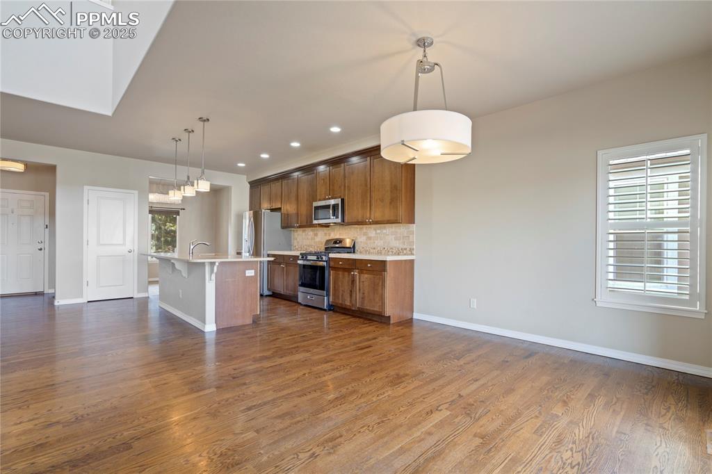Image 49 of 50: Kitchen featuring backsplash, a kitchen bar, stainless steel appliances, ha