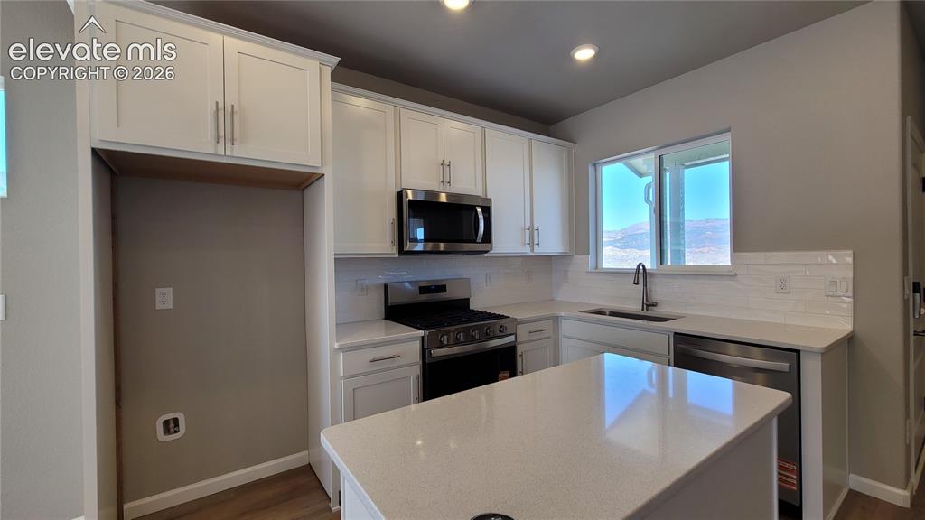 Image 4 of 25: Kitchen with Quartz countertops, stainless steel gas range, microwave, dish