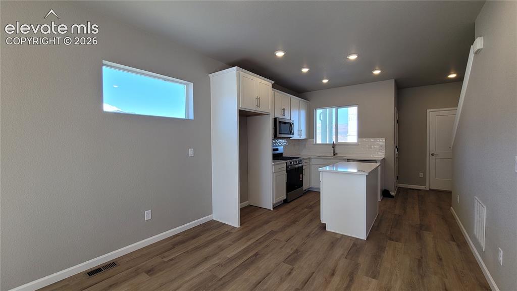 Image 5 of 25: Kitchen with Quartz countertops, stainless steel gas range, microwave, dish