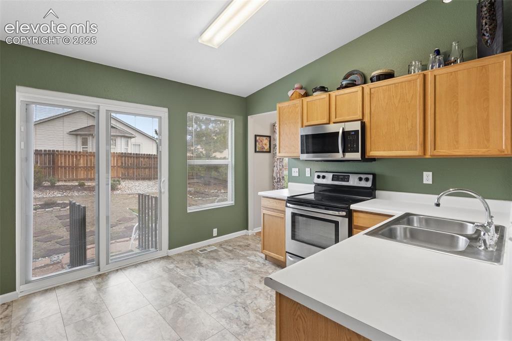 Image 11 of 32: Kitchen featuring wood-finish cabinetry, stainless steel appliances, and a