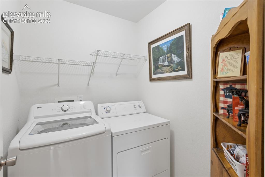 Image 13 of 32: White washer and dryer appliances with overhead wire shelving