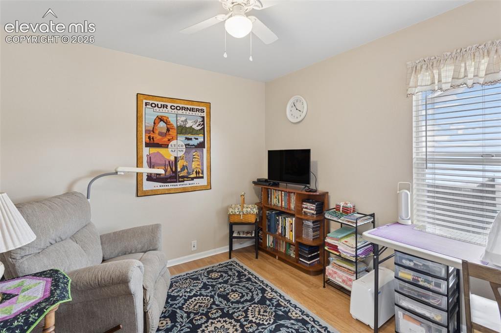 Image 17 of 32: Wood-finish flooring, ceiling fan with light fixture, and a window with bli