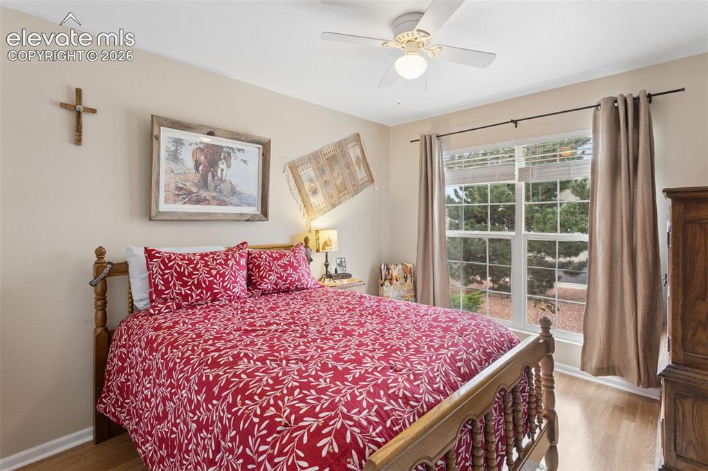 Image 20 of 32: Wood-finish flooring, ceiling fan, and window with exterior landscaping