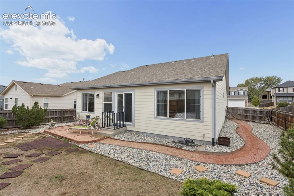 Image 22 of 32: Exterior siding with multiple windows and a sliding glass door out to a fla