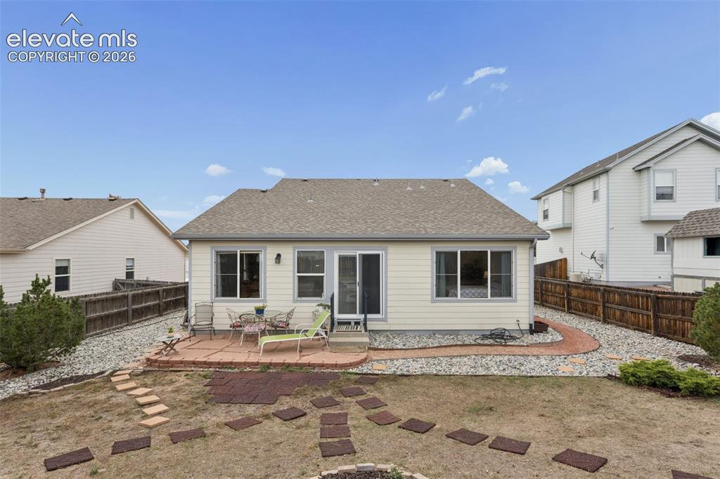 Image 23 of 32: Rear exterior with a flag stone patio, slider door, multiple windows, and p