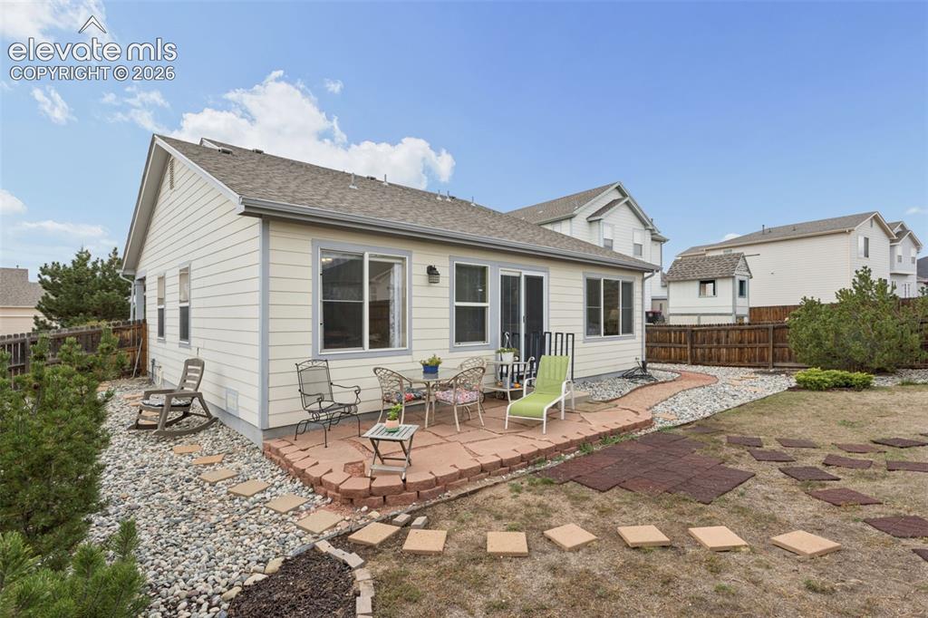 Image 24 of 32: Rear exterior featuring a flagstone patio, sliding glass door, multiple win