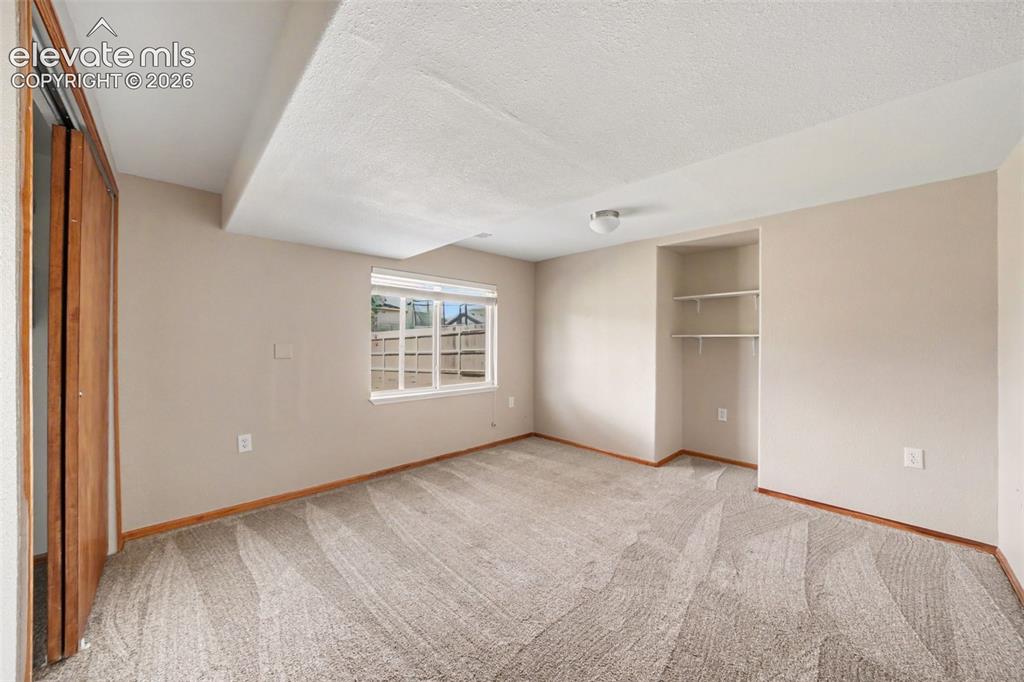 Image 17 of 23: Neutral wall color, window with white blinds, flush-mount ceiling light, bu