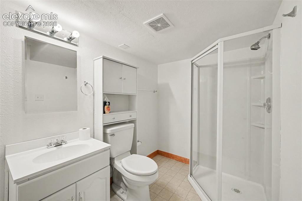 Image 18 of 23: Vanity with integrated sink, glass-enclosed shower, wall-mounted mirror, an