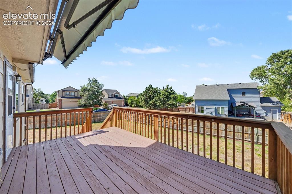 Image 19 of 23: Expansive wooden deck featuring a full railing and an attached retractable 