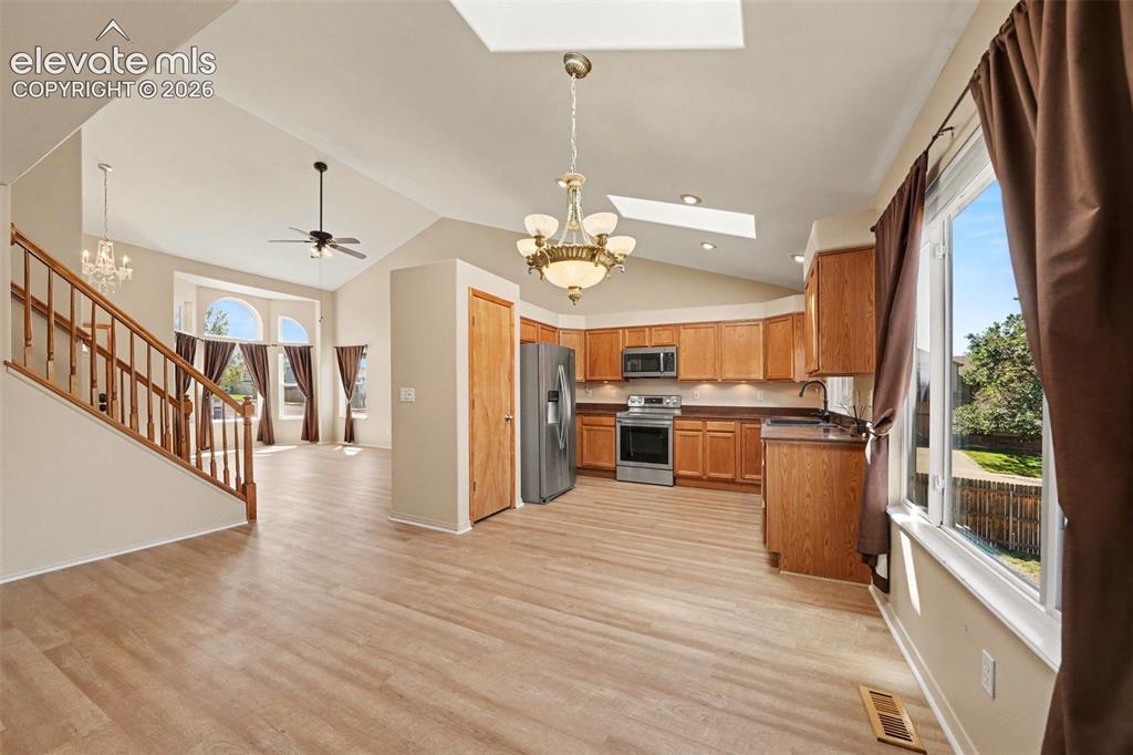 Image 5 of 23: Vaulted ceiling with skylight, wood-finish flooring, kitchen with wood cabi