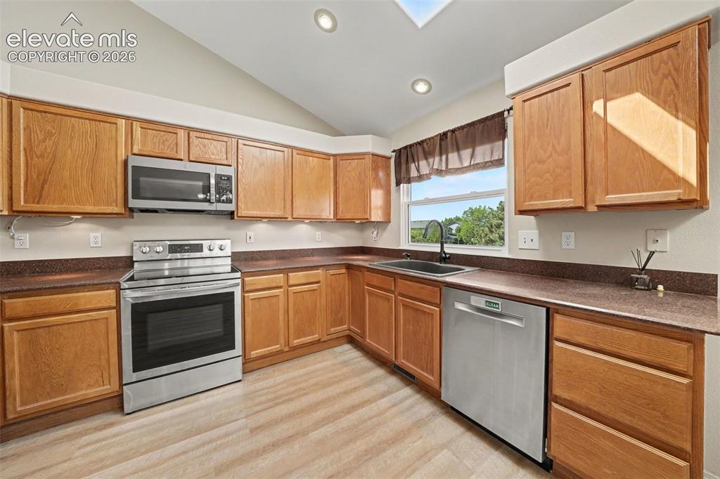Image 8 of 23: Kitchen with wood-finish flooring, recessed lighting, wood cabinetry, stain
