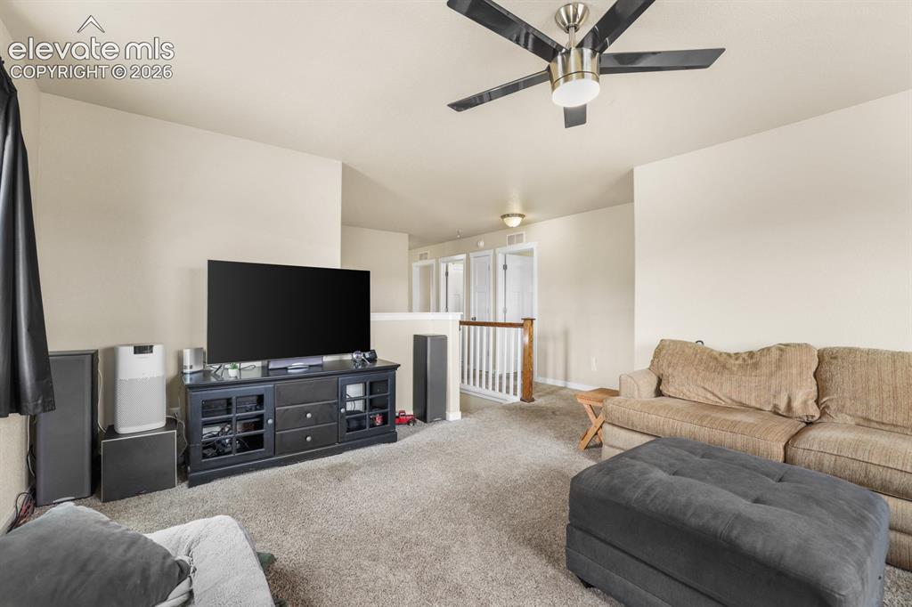 Image 27 of 44: Carpeted living area featuring a ceiling fan with integrated lighting, neut
