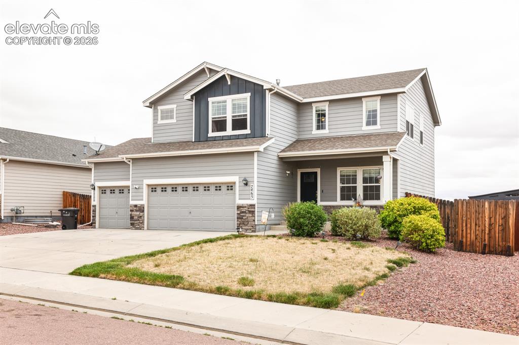 Image 3 of 44: Two-story residence featuring light gray siding with stone veneer accents, 