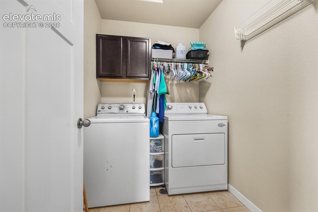 Image 35 of 44: Laundry area featuring tile flooring, wall-mounted shelving, and upper cabi