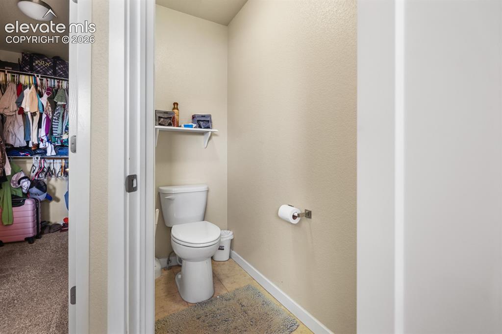 Image 40 of 44: Compact water closet featuring a two-piece toilet, wall-mounted shelving, a