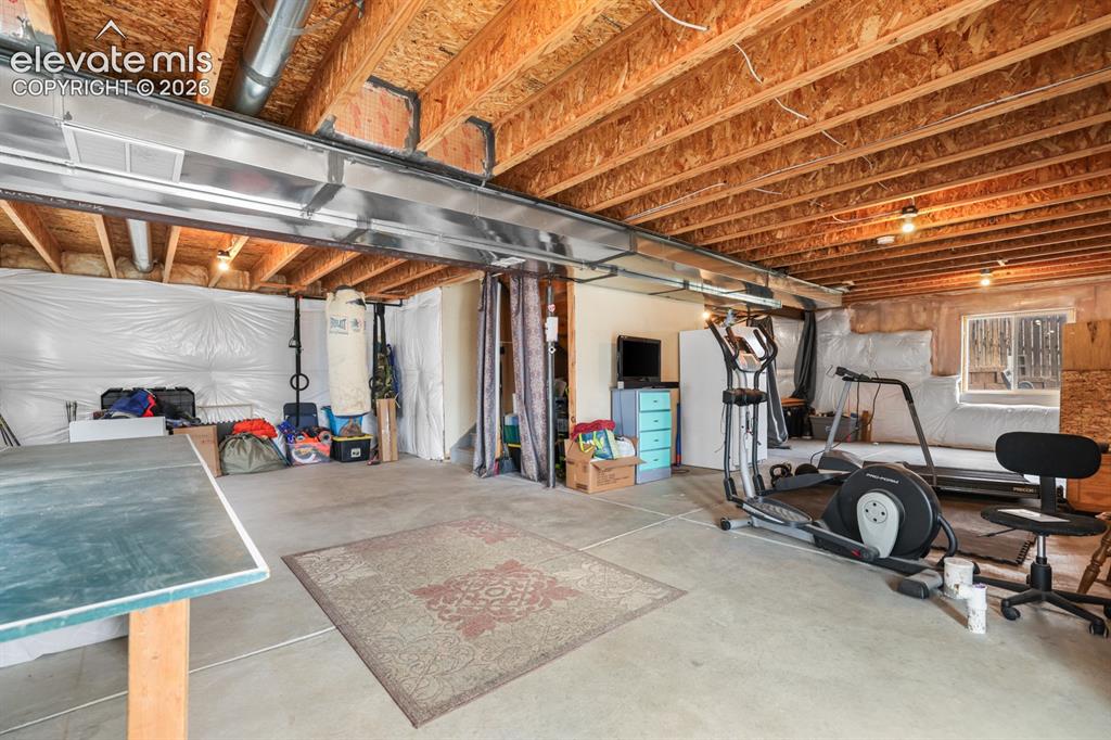 Image 42 of 44: Unfinished basement with exposed ceiling joists and concrete flooring