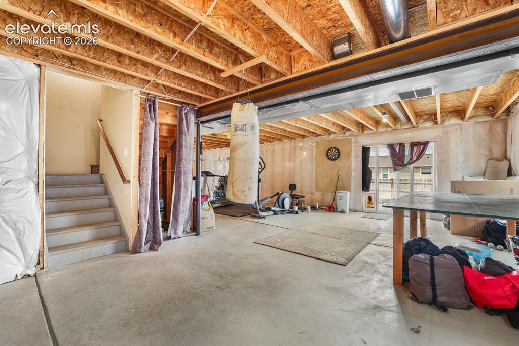 Image 43 of 44: Spacious unfinished basement with exposed wooden joists and structural beam
