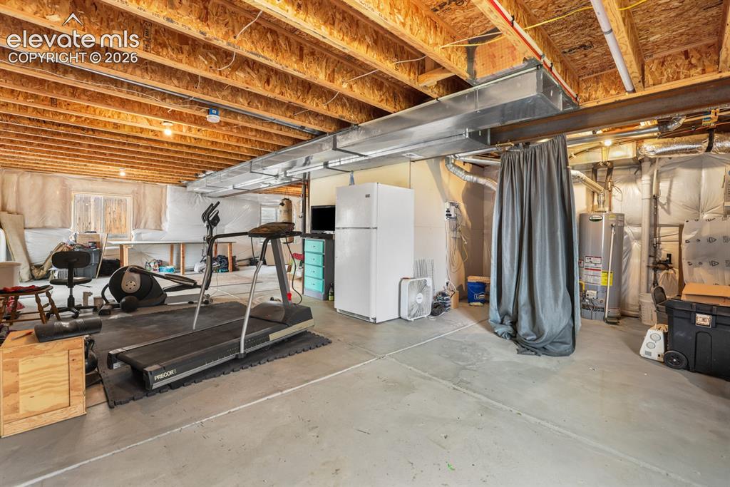 Image 44 of 44: Unfinished lower level featuring concrete flooring, exposed ceiling joists,