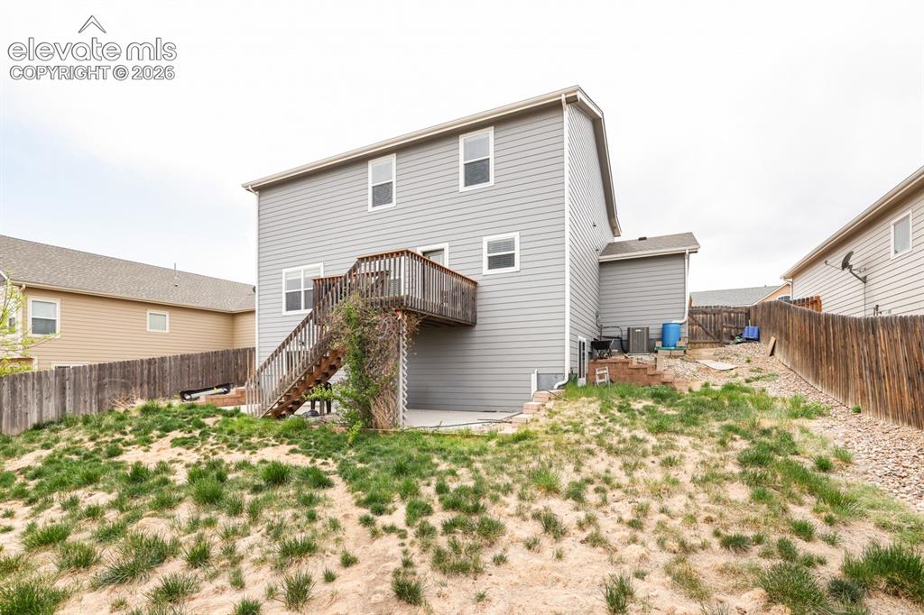 Image 5 of 44: Rear exterior featuring light gray siding, multiple windows, and a raised w