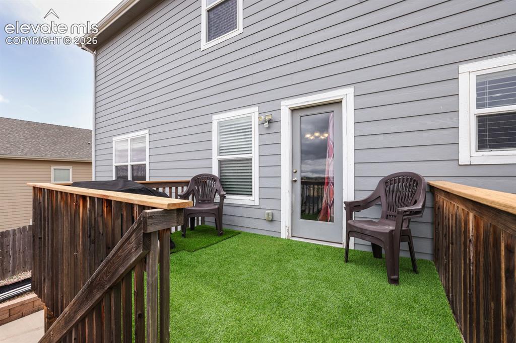 Image 6 of 44: Upper-level deck featuring artificial turf flooring, a wooden railing, a gl
