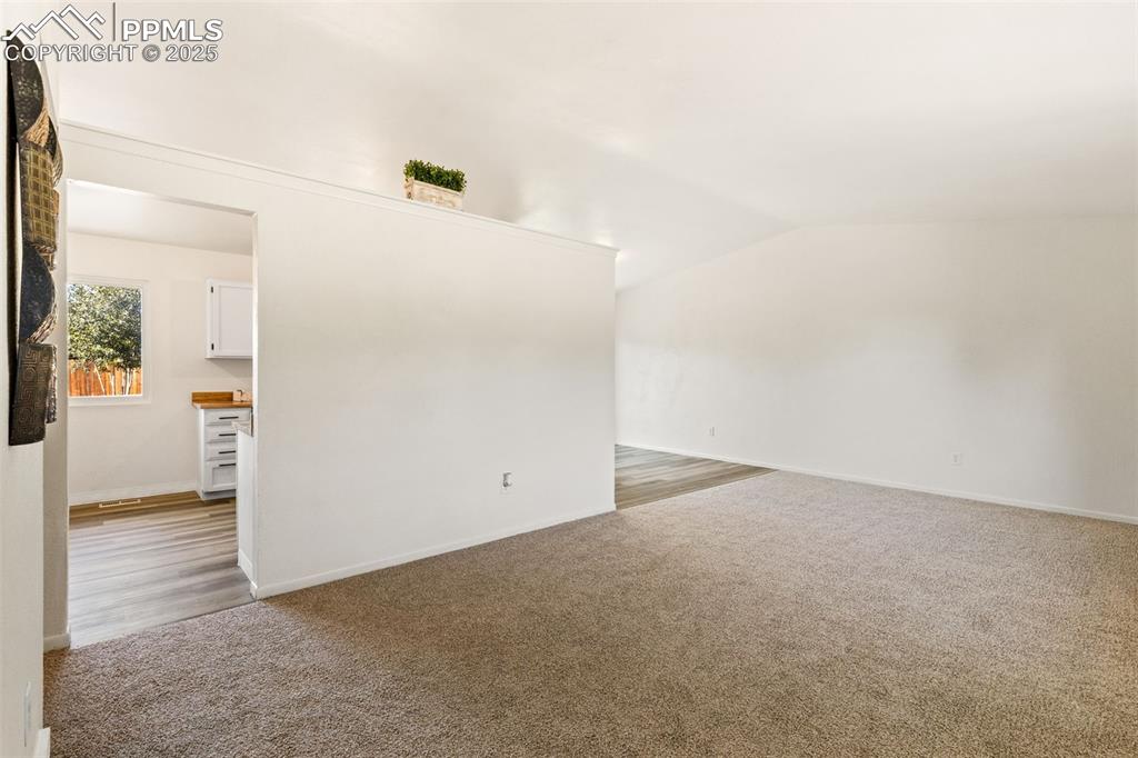 Image 13 of 44: Empty room featuring light carpet and vaulted ceiling