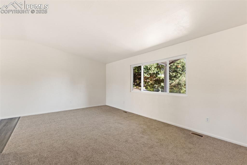 Image 14 of 44: Empty room with lofted ceiling and carpet