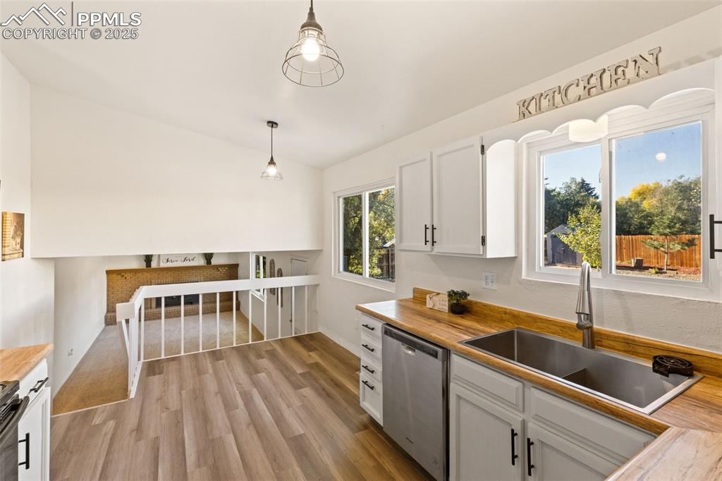 Image 18 of 44: Kitchen with butcher block counters, white cabinetry, stainless steel dishw