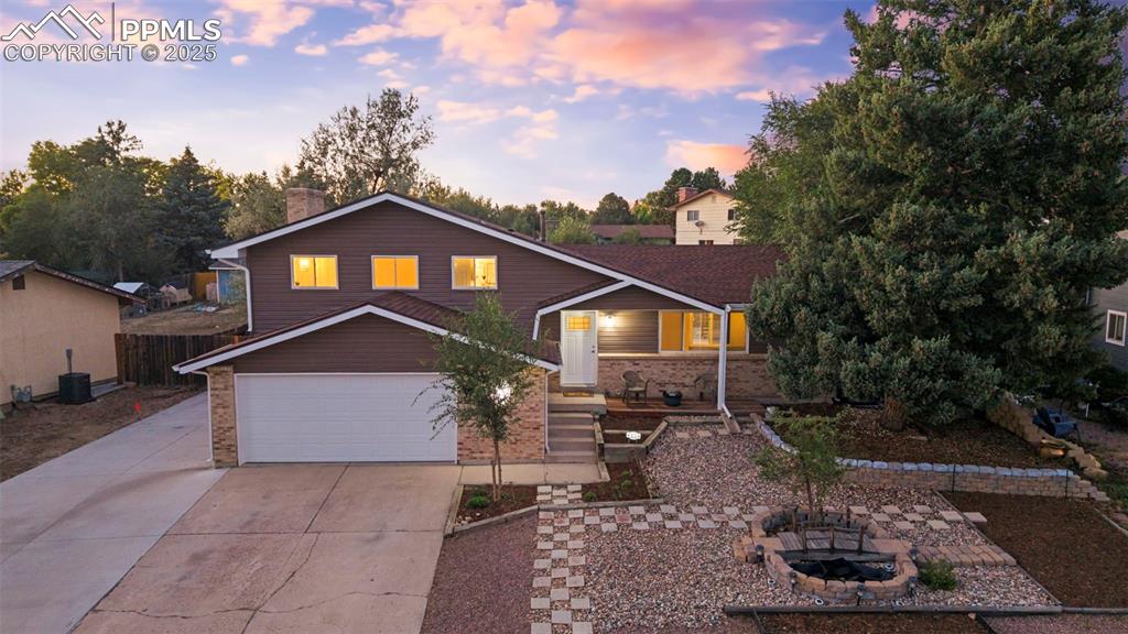Image 2 of 44: View of front of home with a chimney, driveway, an outdoor fire pit, brick 