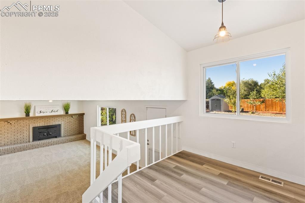 Image 22 of 44: Stairway featuring vaulted ceiling, wood finished floors, and a wood stove