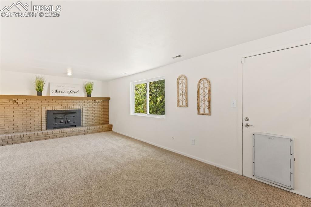 Image 23 of 44: Unfurnished living room featuring carpet floors and a wood stove