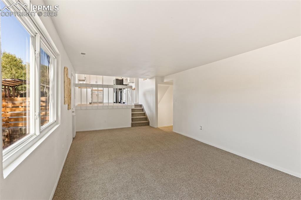 Image 25 of 44: Unfurnished living room with light carpet and stairs