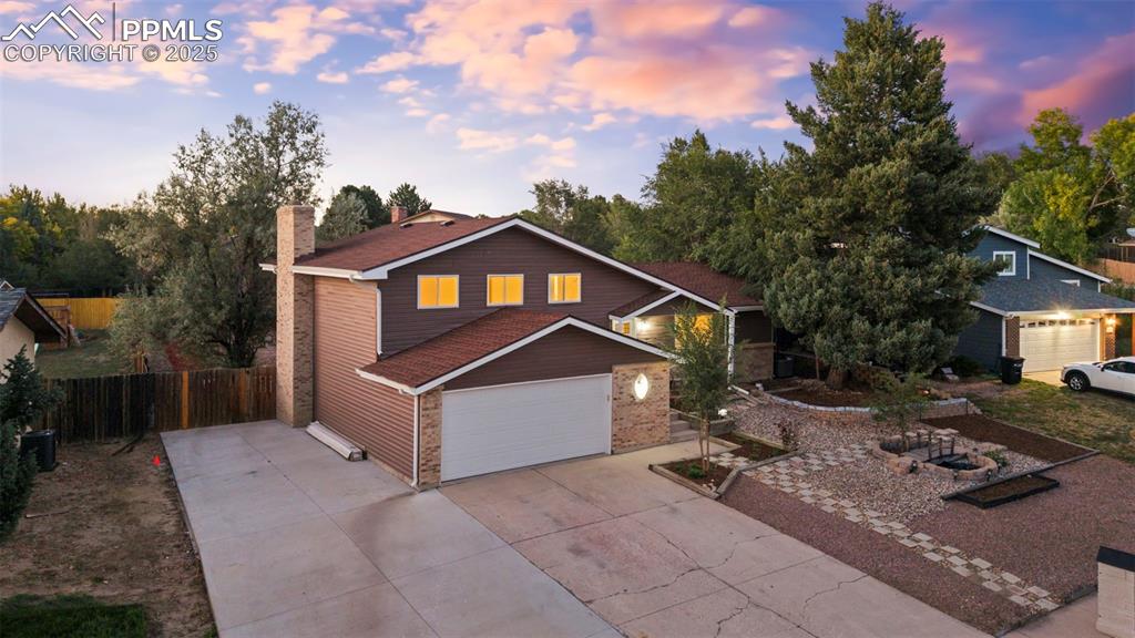 Image 3 of 44: View of front of home with concrete driveway, a chimney, and brick siding