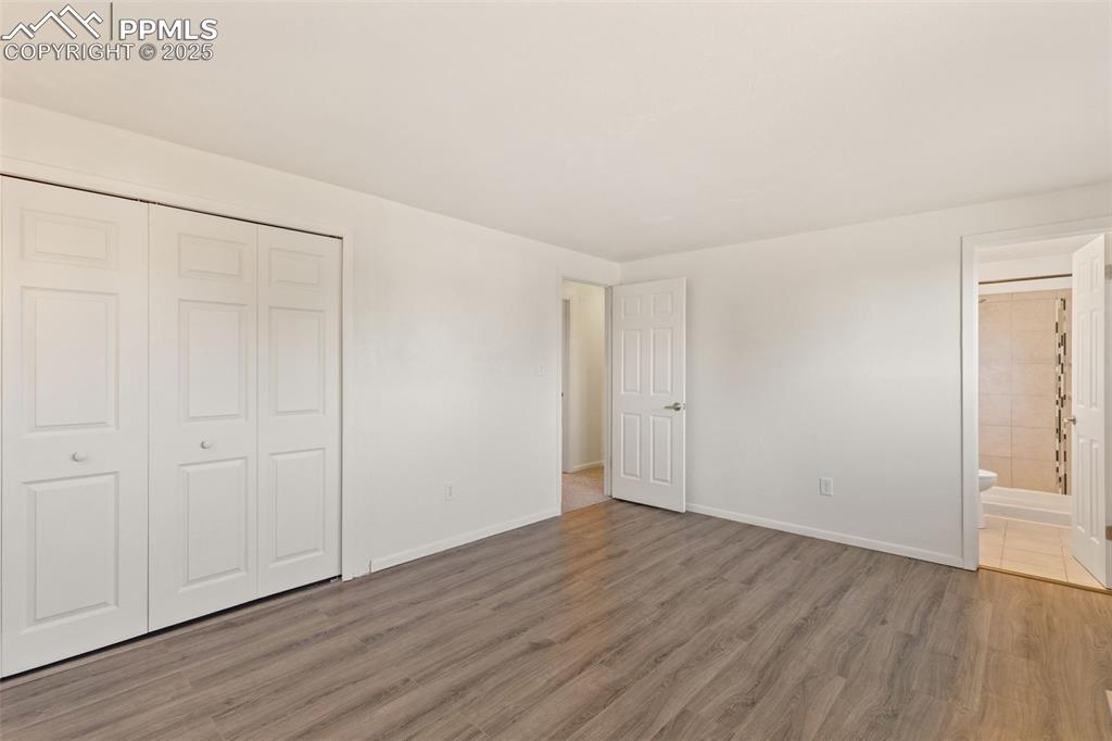 Image 30 of 44: Unfurnished bedroom with wood finished floors, a closet, and connected bath