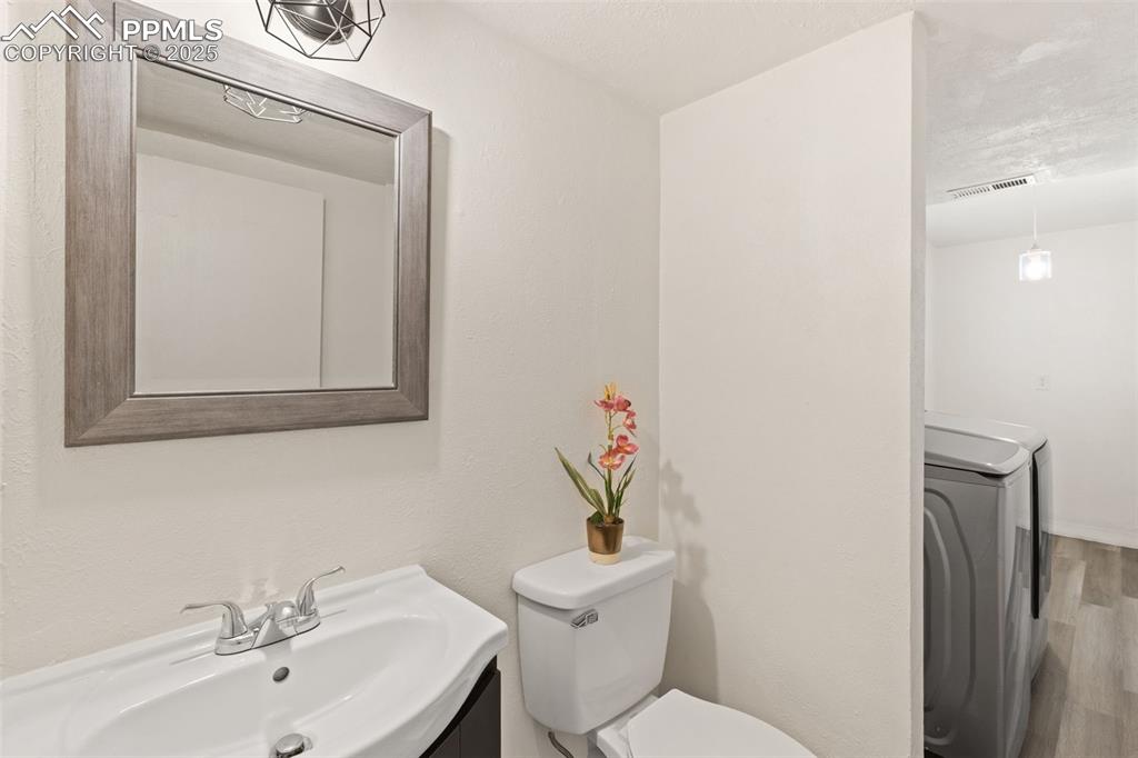 Image 33 of 44: Half bathroom with vanity, wood finished floors, and a textured wall