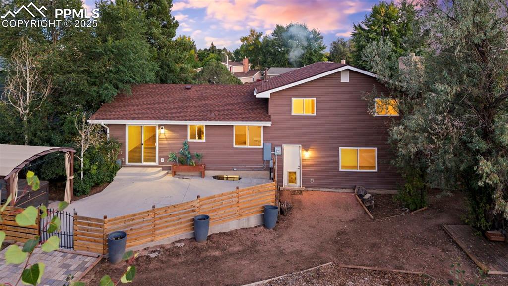 Image 6 of 44: Back of house at dusk featuring roof with shingles and a patio area